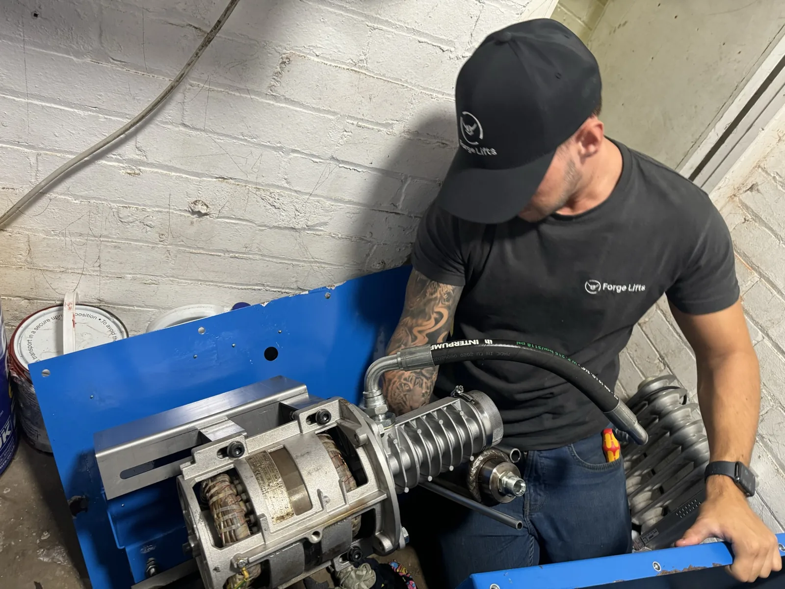 Forge Lifts engineer working beside a lift motor and machinery